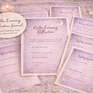May include: A collection of lavender-themed items, including a candle, a key, and several cards with text that reads "Calm Evening Reflection Journal" and "Nightly Gratitude." The cards have a soft, purple and white color scheme.