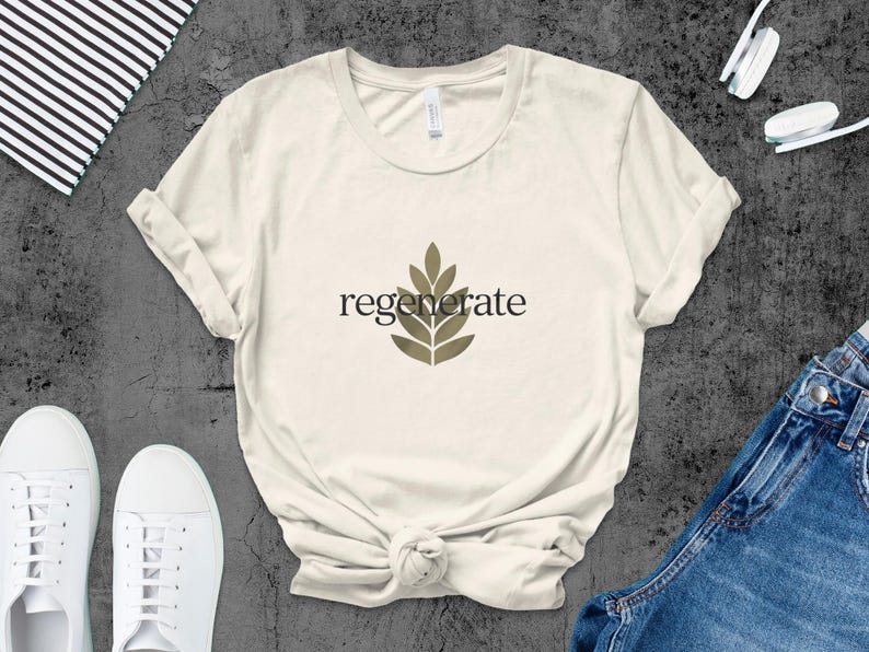 Puede incluir: Camiseta color crema con la palabra "regenerate" en fuente negra y un dise&ntilde;o de hojas. La camiseta se combina con zapatillas blancas y vaqueros azules. Tambi&eacute;n se ven un cuaderno y unos auriculares.