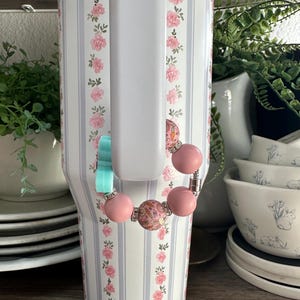 Op de afbeelding: Een set van drie keramische mokken met een gespikkelde, matte afwerking. De mokken zijn in cr&egrave;me, lichtgrijs en donkergrijs. Elke mok heeft een eenvoudig, minimalistisch ontwerp.