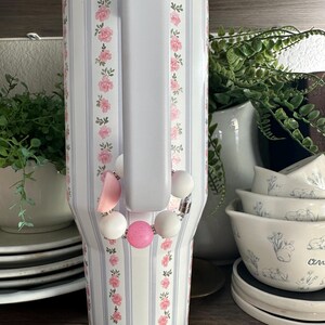 K&ouml;nnte beinhalten: Handgefertigtes Holzschild mit dem Wort "Welcome" in verspielter Schrift. Das Schild ist wei&szlig; lackiert mit einem Used-Look und mit einem floralen Design in Rosa- und Gr&uuml;nt&ouml;nen verziert. Es misst ca. 30 cm breit und 15 cm hoch.