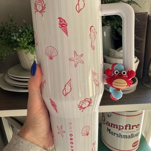 May include: White HydroJug with red seashell, starfish, and ice cream cone designs. The jug has a large white handle and a red crab charm. The text "HYDROJUG" is printed on the side.