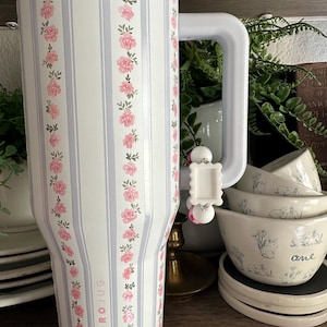 May include: White Hydro Jug with pink floral and vertical stripe design. The jug has a pink rim and a white handle. The text "HYDRO JUG" is printed on the side. The jug is next to a set of white bowls with a bunny design.