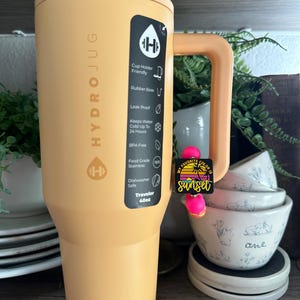 以下が含まれることがあります： 黒いハンドルが付いた白いセラミックマグカップで、太字の黒いフォントで「But First, Coffee」と書かれています。 マグカップはニュートラルな背景に置かれ、シンプルなデザインを際立たせています。