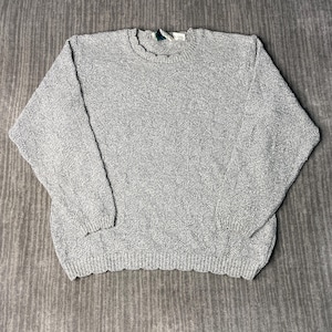 May include: A light gray, textured knit sweater with a crew neck and long sleeves. The sweater has a ribbed hem and cuffs. The fabric has a speckled appearance.