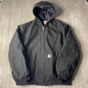 May include: A black hooded jacket featuring a full-length front zip, a quilted interior lining, and ribbed cuffs at the sleeves and waist. The garment includes a small rectangular logo patch on the front pocket and a drawstring hood.
