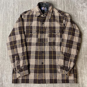 Peut inclure: Une chemise à manches longues boutonnée avec un motif à carreaux marron, beige et jaune. La chemise présente un col pointu, deux poches de poitrine à rabat boutonné et une doublure intérieure matelassée sombre visible au col et aux poignets.