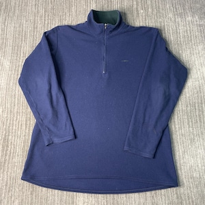 May include: A navy blue fleece pullover with a quarter-zip closure and a green collar. The long-sleeved shirt has a small logo on the chest. The garment is laid flat on a neutral surface.