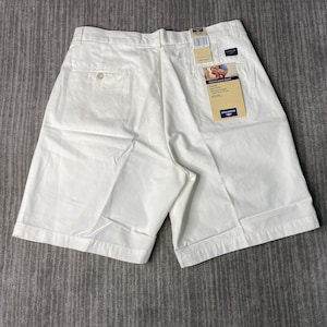 May include: White Dockers brand men's shorts with a button closure and two back pockets. The shorts have a tag attached with product information. The shorts are made of a lightweight fabric and are designed for a comfortable fit.
