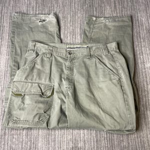 May include: Olive green cargo pants with multiple pockets and a button closure. The pants have a relaxed fit and show some wear and tear. The label reads "Khakis".