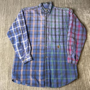 May include: A long-sleeved button-down shirt with a patchwork plaid design in shades of blue, green, pink, and orange. The shirt has a button-down collar, a chest pocket, and buttoned cuffs. The shirt is made of a soft, woven fabric.