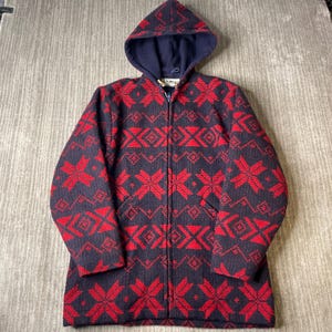 May include: A navy blue and red zip-up hooded jacket featuring a repeating geometric snowflake pattern throughout. The garment includes a full-length front zipper, a hood, and two front pockets. The L.L.Bean brand label is visible at the inner neck.