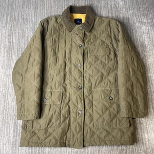 May include: An olive green quilted jacket featuring a diamond-patterned exterior, a brown corduroy collar, and a bright yellow interior lining. The jacket includes a front button closure, two lower flap pockets with buttons, and a single chest pocket.