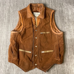 May include: A brown suede vest featuring a quilted brown lining, a fold-down collar, and a front closure with five silver-toned metal snaps. The garment includes three zippered pockets with silver-toned hardware and a label reading Berman's.