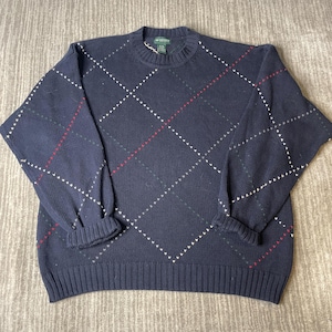 May include: Navy blue argyle sweater with white, red, and green accents. The sweater has a ribbed hem and cuffs, and a crew neck. The argyle pattern is a classic design.