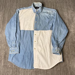 May include: A long-sleeved button-down shirt with a color-block design. The shirt features light blue denim and cream-colored panels. It has a button-down collar and cuffs. The brand name "FRASER BAY" is visible on the collar.