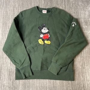 May include: A dark green sweatshirt with a Mickey Mouse graphic. The cartoon mouse has a red belly, yellow shoes, and black ears. The sleeve has the word "Mickey" with a thumbs up. The sweatshirt has a crew neck and ribbed cuffs.