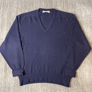 Puede incluir: Un su&eacute;ter de manga larga en color azul marino s&oacute;lido con cuello en V, pu&ntilde;os acanalados y dobladillo acanalado. La prenda cuenta con una etiqueta blanca en el cuello interior y est&aacute; confeccionada en tejido de punto con dise&ntilde;o cl&aacute;sico.