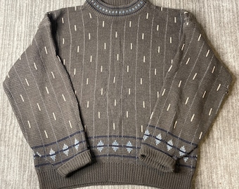 May include: A brown long-sleeve sweater featuring a mock neck collar with blue accents. The body and sleeves are decorated with a vertical pattern of small white dashes, while the cuffs and hem display a horizontal band of blue diamond shapes.
