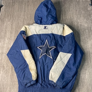 May include: Blue and white vintage Starter jacket with a hood. Features a large white star with a blue center on the back, and the NFL logo on the left sleeve. The jacket has a blue body with white and cream-colored accents.