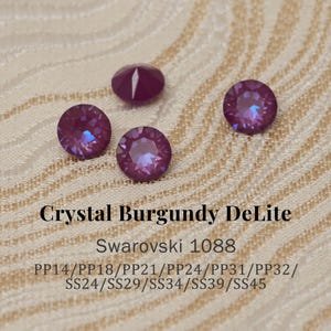 Puede incluir: Cuatro cristales Swarovski Crystal Burgundy DeLite. Los cristales redondos tienen múltiples facetas, reflejando la luz con una iridiscencia púrpura y azul. El texto en la imagen dice "Crystal Burgundy DeLite Swarovski 1088".