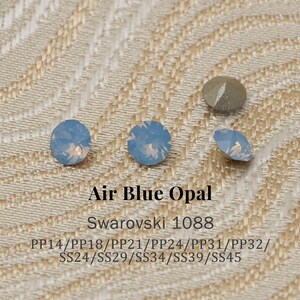 Op de afbeelding: Air Blue Opal Swarovski kristallen in verschillende vormen en maten. De afbeelding toont verschillende ronde en ovale kristallen, samen met een metaalkleurig kristal. De tekst "Air Blue Opal" en "Swarovski 1088" zijn zichtbaar.