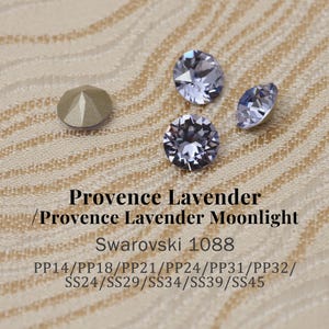 May include: Close-up of several Swarovski crystals in shades of lavender and gold. The crystals are round and faceted, reflecting light. Text on the image reads "Provence Lavender / Provence Lavender Moonlight Swarovski 1088".