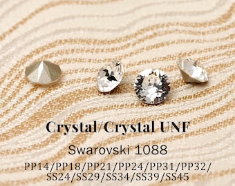 May include: Four clear, faceted, round crystals are displayed. Text reads: Crystal/Crystal UNF, Swarovski 1088, PP14/PP18/PP21/PP24/PP31/PP32/SS24/SS29/SS34/SS39/SS45. The crystals have a pointed back and a brilliant, multi-faceted top surface.