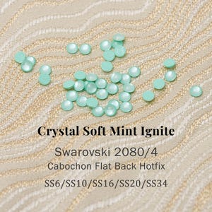 May include: A collection of small, round, mint green cabochon flat back hotfix crystals. The text reads: Crystal Soft Mint Ignite, Swarovski 2080/4, Cabochon Flat Back Hotfix, SS6/SS10/SS16/SS20/SS34. These circular embellishments have a smooth finish.