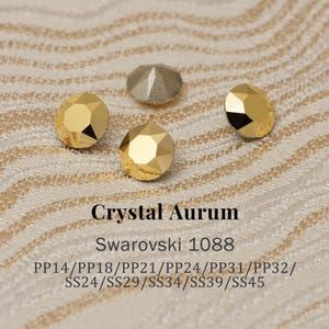 May include: Close-up of several faceted crystal rhinestones in gold and gray. The text "Crystal Aurum" and "Swarovski 1088" are displayed below the crystals, along with size codes.