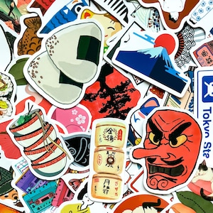 May include: A collection of Japanese-themed stickers featuring illustrations of onigiri, Mount Fuji with a red sun, a red tengu mask, and stacked bowls of ramen. Other stickers include sushi, cherry blossoms, and vintage cassette tapes.