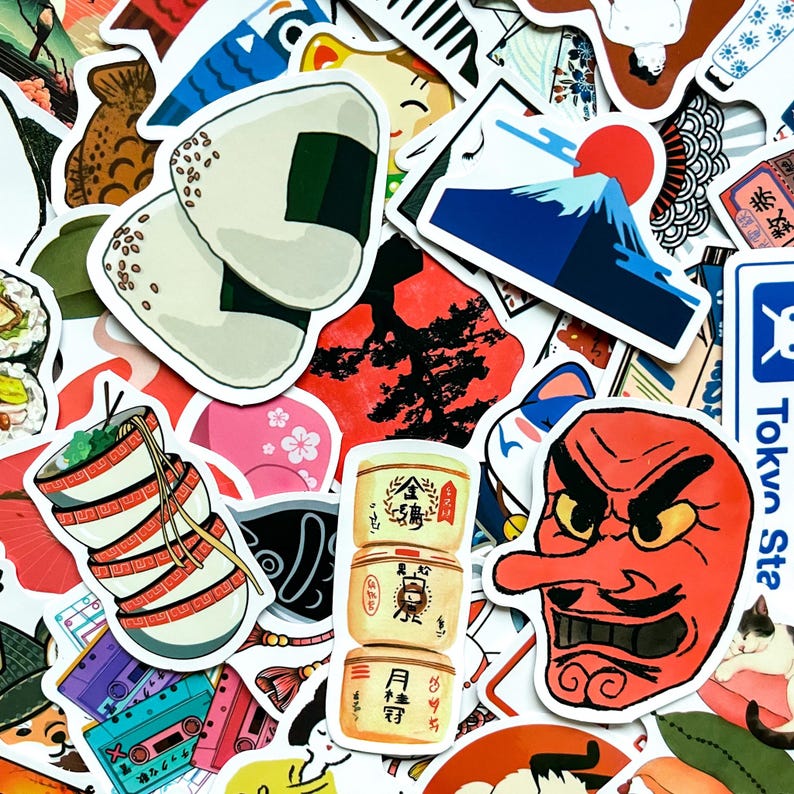 May include: A collection of Japanese-themed stickers featuring illustrations of onigiri, Mount Fuji with a red sun, a red tengu mask, and stacked bowls of ramen. Other stickers include sushi, cherry blossoms, and vintage cassette tapes.