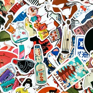 May include: A collection of colorful Japanese-themed stickers. The stickers feature illustrations of traditional Japanese items such as a carp streamer, wind chimes, lanterns, and a bottle of Ramune soda. The word "JAPAN" is visible on one sticker.