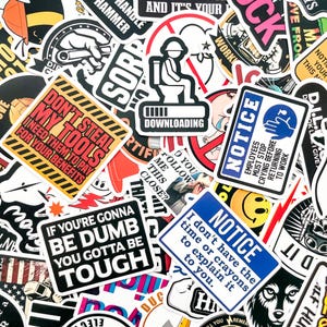 Puede incluir: Una colección de pegatinas variadas con texto y gráficos llamativos. Las pegatinas incluyen frases como "Don't Steal My Tools", "If You're Gonna Be Dumb, You Gotta Be Tough" y "Notice: I don't have the time or crayons to explain it to you."