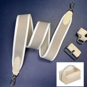 Puede incluir: Una correa de bolso a rayas beige y blanco con cierres plateados y detalles de cuero. Incluye herrajes a juego y un pequeño bolso beige con una raya blanca y asa. Accesorios para bolsos.