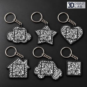 May include: Six black and white keychains featuring QR codes in various shapes including a cloud, star, heart, house, car, and square. Each keychain has a silver metal ring and chain. The top right corner displays the text 3D PRINT LAB.