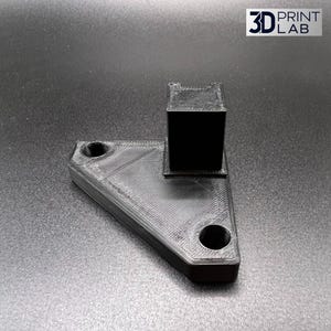 Puede incluir: Un soporte negro impreso en 3D con un poste rectangular y dos agujeros circulares. El soporte tiene forma triangular y tiene una superficie texturizada. El logotipo "3D PRINT LAB" está en la esquina superior derecha.