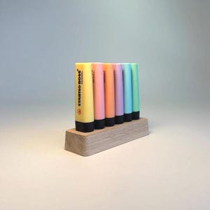 May include: A collection of Stabilo Boss highlighters in various pastel colors, including yellow, pink, orange, purple, blue, and green. The highlighters are displayed in a wooden holder. The text "STABILO BOSS ORIGINAL" is visible on the yellow highlighter.