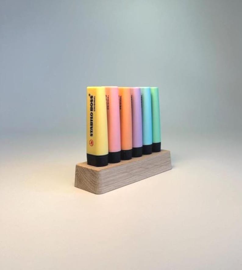 May include: A collection of Stabilo Boss highlighters in various pastel colors, including yellow, pink, orange, purple, blue, and green. The highlighters are displayed in a wooden holder. The text "STABILO BOSS ORIGINAL" is visible on the yellow highlighter.