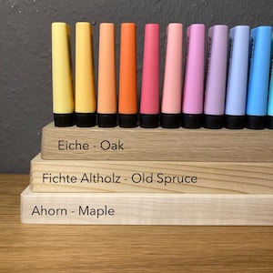 May include: A collection of colorful, conical-shaped markers in shades of yellow, orange, pink, purple, and blue, arranged on wooden blocks. The blocks are labeled with wood types: Oak, Old Spruce, and Maple.