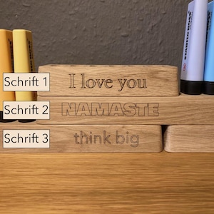 May include: Wooden desk organizers with engraved text. The top organizer says "I love you", the middle one says "NAMASTE", and the bottom one says "think big". Colorful highlighters are in the background.