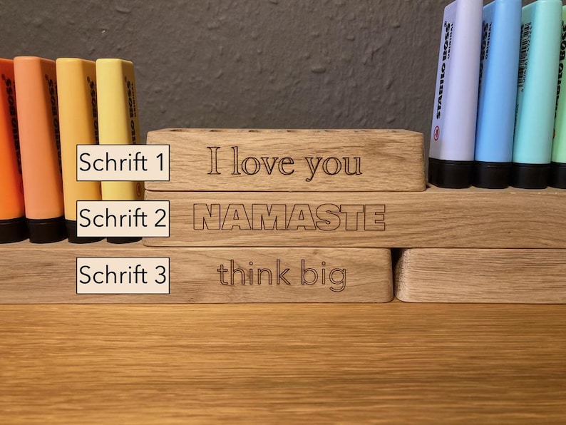 May include: Wooden desk organizers with engraved text. The top organizer says "I love you", the middle one says "NAMASTE", and the bottom one says "think big". Colorful highlighters are in the background.