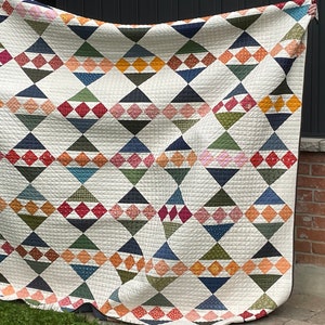 May include: A large quilt featuring a geometric design of triangles and diamonds in shades of blue, green, red, orange, and white.
