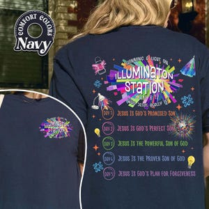 May include: Navy blue t-shirt with the text "ILLUMINATON STATION" in a colorful design. The back of the shirt features additional text and graphics, including "Shining a light on" and Bible verses.
