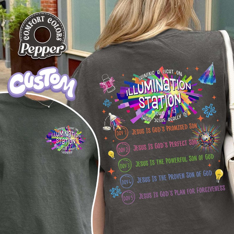 K&ouml;nnte beinhalten: Ein dunkelgraues T-Shirt mit einer bunten Grafik auf der R&uuml;ckseite und einer kleineren Version auf der Vorderseite. Das Design enth&auml;lt den Text Shining a Light on Illumination Station, John 8:12 und eine Liste von f&uuml;nf Tagesthemen mit Lichtsymbolen.
