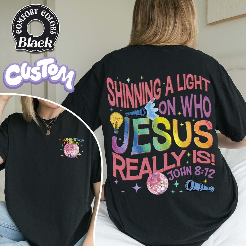 May include: Black t-shirt with the text "SHINNING A LIGHT ON WHO JESUS REALLY IS! JOHN 8:12" in colorful letters. The shirt also features a graphic of a lightbulb, telescope, and a glittery sphere. The front of the shirt has the text "ILLUMINATION STATION".