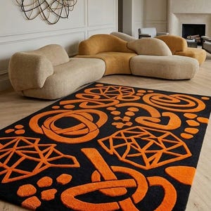 May include: A contemporary living room with a black rug featuring an abstract orange pattern. The room also includes a curved mustard sofa, a beige sofa, and a decorative wall sculpture.