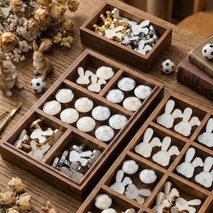 May include: Wooden trays filled with decorative cabinet knobs in various designs. The knobs feature soccer ball and bunny shapes in gold, silver, and white. Small soccer balls and bunny figurines are also present.