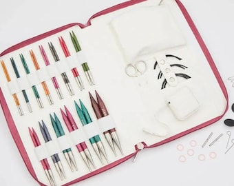 May include: A red zipped case containing a set of colourful interchangeable knitting needles, a white fabric pouch, a pair of scissors, and a set of circular needles. The case also includes a small white pouch, a set of stitch markers, and a set of needle tips.