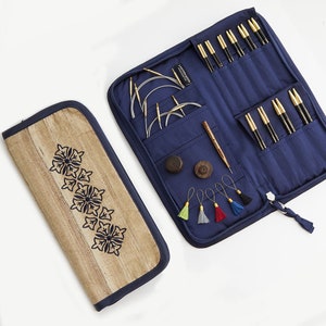 May include: A blue zippered case with a variety of knitting needles, stitch markers, and other accessories. The case is open and the needles are visible. The case is made of a durable fabric and has a zipper closure. The case is also decorated with a floral design.