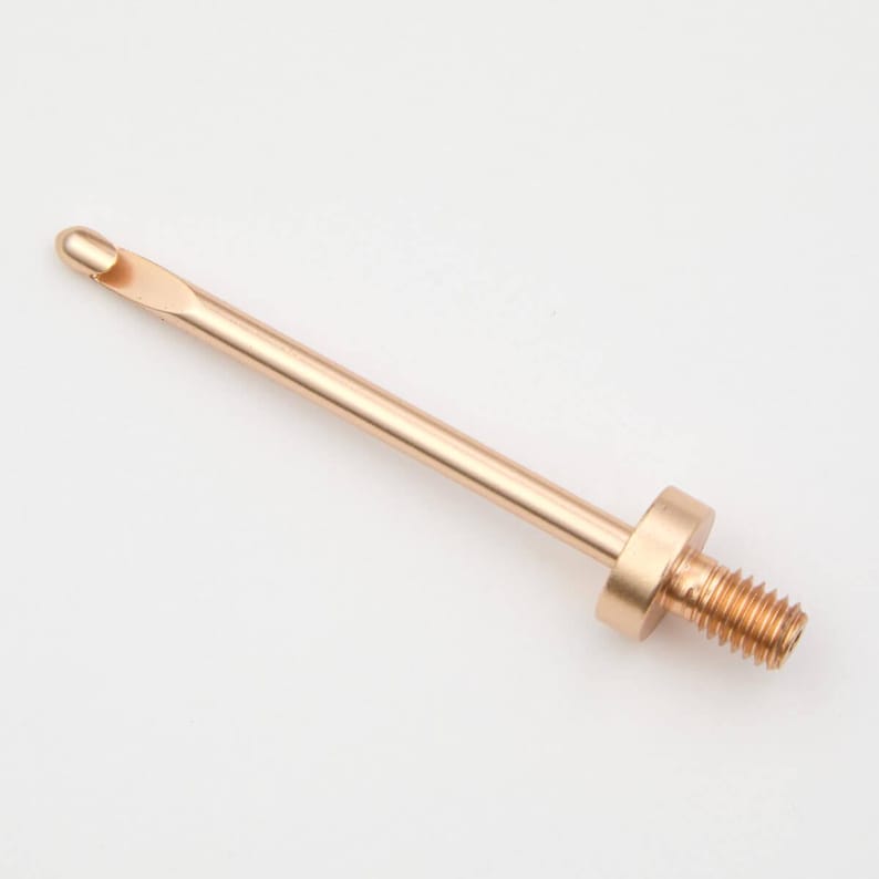 May include: A gold-coloured metal crochet hook with a threaded end. The hook is approximately 15 cm long.